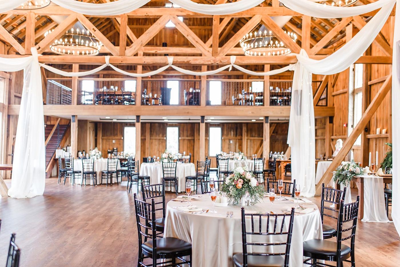 The barn set for a reception, with chandeliers and timber trusses
