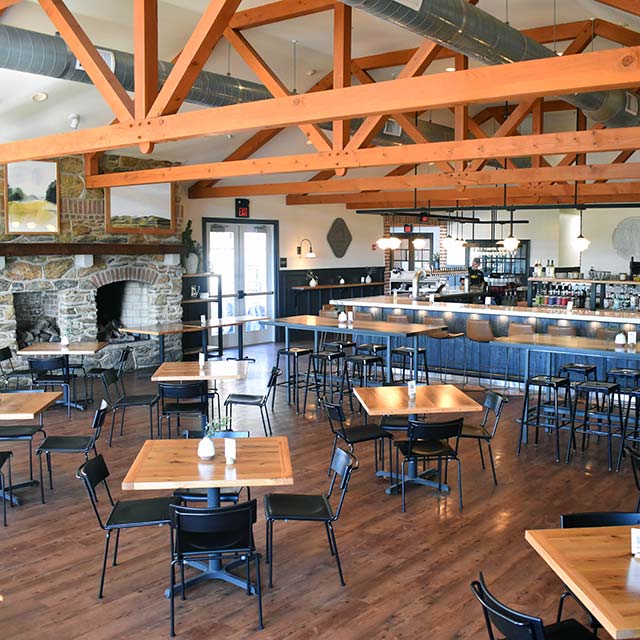 The Wyndridge dining room, with timber trusses, a stone fireplace and the bar